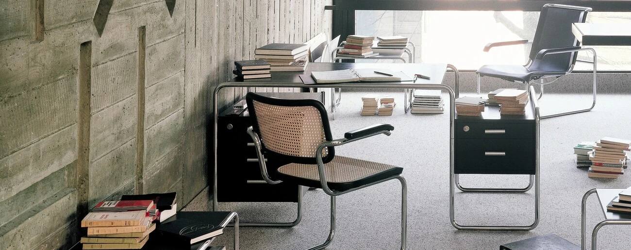 Schreibtisch und Stuhl in inem Arbeitszimmer voll Bücher